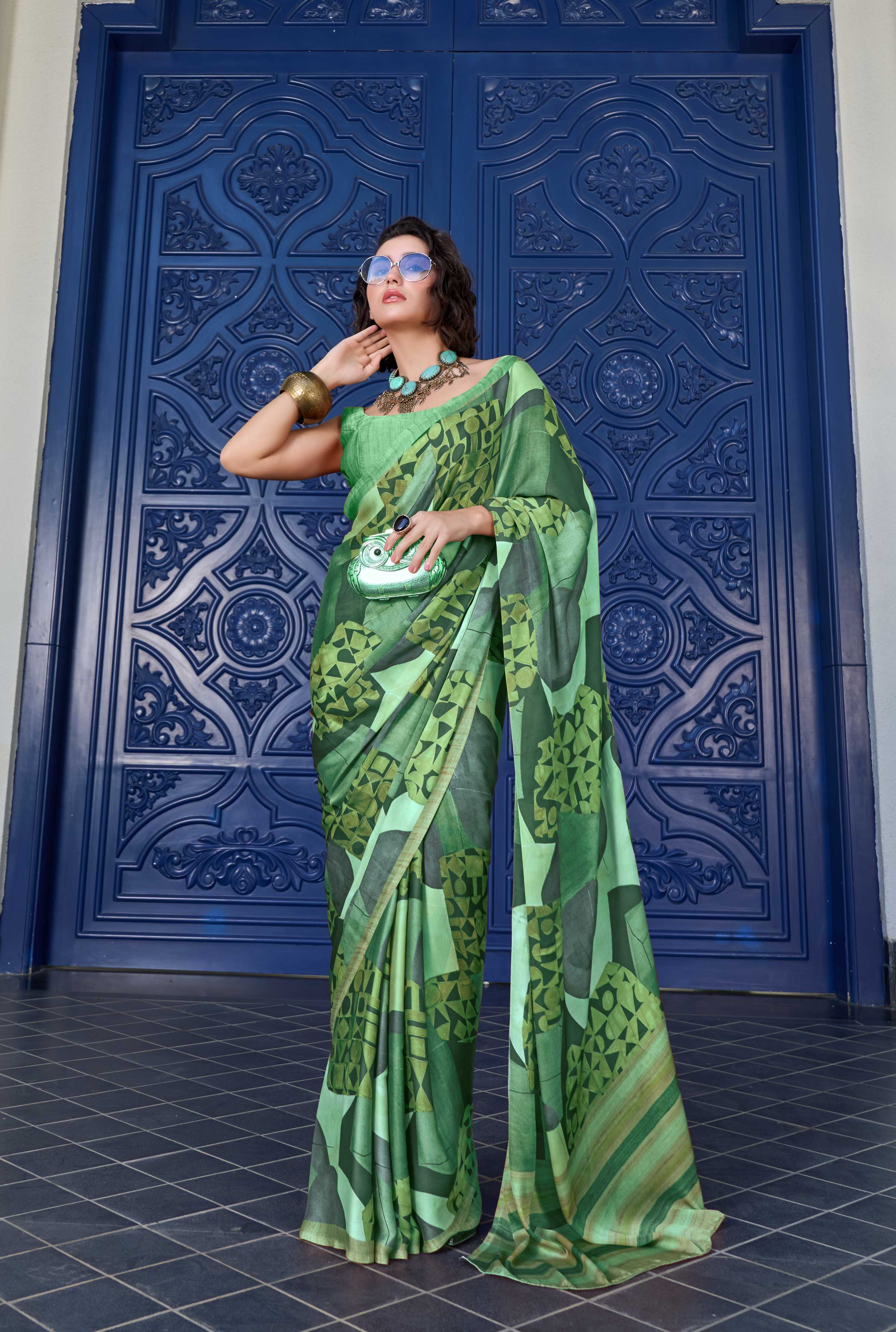 Woman in a green saree standing in front of a blue decorative door.